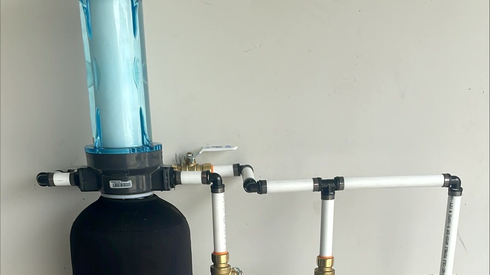 A HomeWater whole-home filter and its plumbing tie-in on a garage wall.